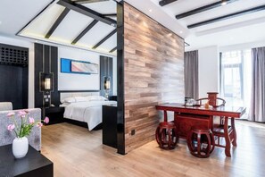 A modern hotel room with a bed, bedside table, and a dining area with stools. - Yunti Hotel (Pingbian)