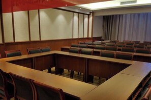 A conference room with a long table and multiple chairs, a large window with curtains, and a plain wall with a panel design. - Yunti Hotel (Pingbian)
