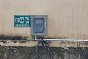 A charging station with a sign, a cable, and a wall-mounted box. - Yunti Hotel (Pingbian)