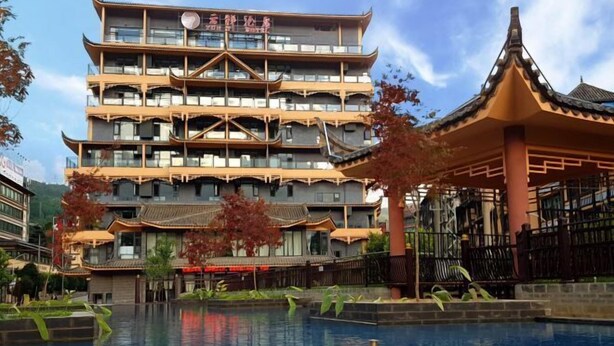 A traditional multi-story building with a pagoda-style roof, a swimming pool, and a well-maintained garden area. - Yunti Hotel (Pingbian)