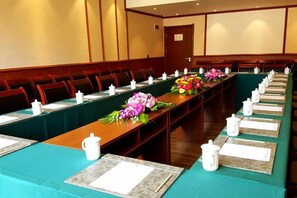 Un salón de conferencias con una mesa larga, sillas y centros de mesa con flores.