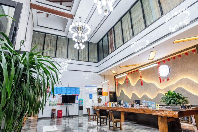 A hotel lobby with a reception desk, seating area, and large windows.