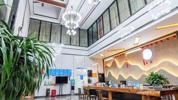 A hotel lobby with a reception desk, seating area, and large windows.