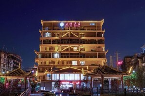 A multi-story building with traditional architectural features, including tiered roofs and illuminated signage. - Yunti Hotel (Pingbian)