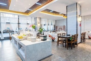 Un comedor moderno de hotel con mostradores de mármol, sillas de madera y una barra de buffet.