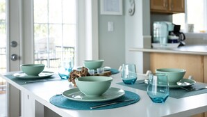 Una cocina moderna con una encimera larga, individuales y cuencos y vasos verde azulado.
