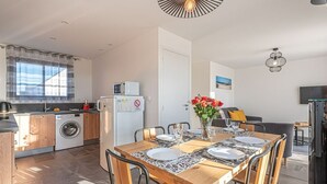 Une cuisine moderne avec un coin repas, comprenant une table dressée pour quatre personnes, un lave-linge et un réfrigérateur.