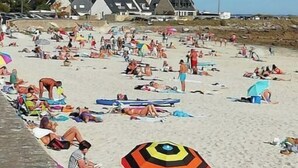 Une plage bondée où les gens se prélassent au soleil et se baignent.