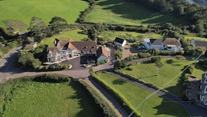 A coastal property with multiple houses, a main building with a driveway, and a road leading to the sea. - The Seaside Inn (Seaton)
