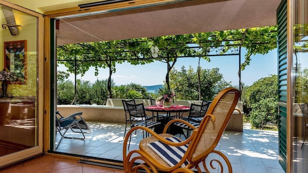 Une terrasse avec une table et des chaises, donnant sur un espace verdoyant et un paysage lointain.