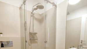 A modern bathroom with a glass-enclosed shower, a white toilet, and a sink with a wooden shelf. - Lisbon Skyline Apartment by Misha s Place 5E (Lisbon)