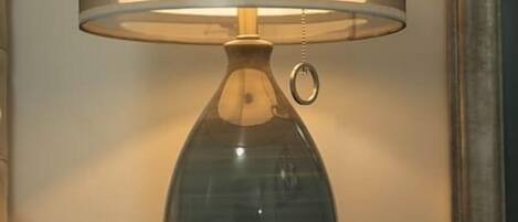 Eine Tischlampe mit einem klaren Glasenschirm und einem Metallfuß, platziert auf einer Holzfläche.