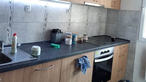A modern kitchen with wooden cabinets, a stainless steel countertop, and a built-in oven. - Stunning Color 1-bed Apartment in Skopje (Skopje)