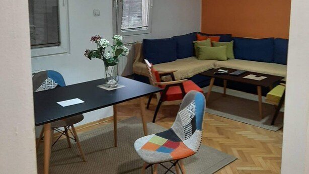 A compact living space with a dining area, a sofa set, and a single chair. - Stunning Color 1-bed Apartment in Skopje (Skopje)