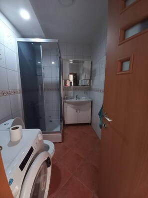A compact bathroom with a shower, toilet, and sink. - Stunning Color 1-bed Apartment in Skopje (Skopje)