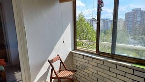 A corner room with a window overlooking a cityscape, a wooden chair, and a tiled floor. - Stunning Color 1-bed Apartment in Skopje (Skopje)
