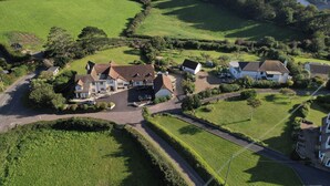 A coastal property with multiple houses, a main building with a driveway, and a road leading to the sea. - The Boat Shed (Seaton)
