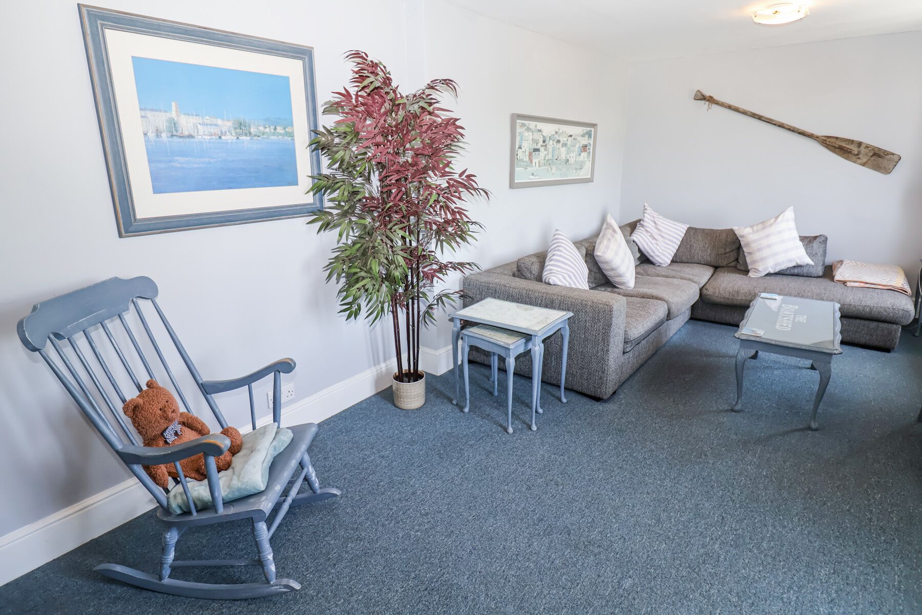 A living room with a rocking chair, a sofa, a coffee table, and a potted plant.