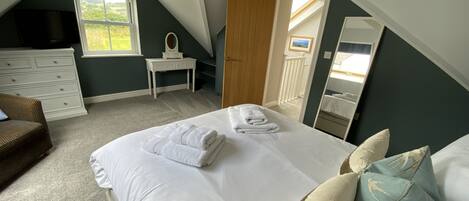 Une chambre à coucher avec un grand lit, une commode, une coiffeuse et une fenêtre.