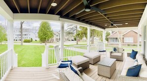 A covered porch with outdoor furniture, a view of a residential neighborhood, and a clear sky.