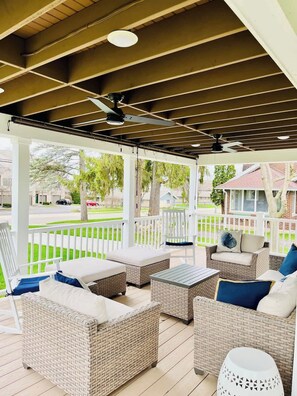 A covered outdoor seating area with wicker furniture, a ceiling fan, and a view of the street. - Modern Farmhouse with Porch near Lake & Downtown (Green Lake)