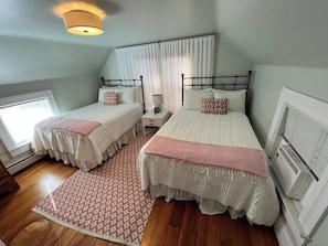 A bedroom with two beds, a window, a heater, and a patterned rug. - Modern Farmhouse with Porch near Lake & Downtown (Green Lake)