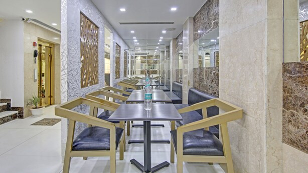 A modern restaurant with marble walls, glass partitions, and a long counter with seating. - Treebo Jannat Residency (New Delhi)