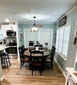 A kitchen with a dining table, chairs, a chandelier, and a coffee machine. - Newly Renovated & 5-Minute Walk to the Beach - Golf Cart Included (Surfside Beach)