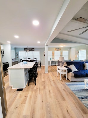 A spacious living area with a kitchen, dining table, and a blue sofa.