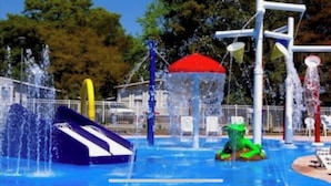 Een waterpark met glijbanen, een waterpretgedeelte en een rode luifel.