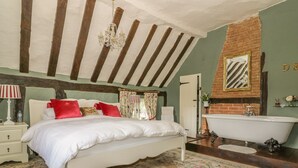 Ein Schlafzimmer mit einem großen Bett, einer weißen Badewanne und einem Kronleuchter.
