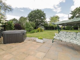 Un patio con hidromasaje, una zona de estar cubierta y césped.