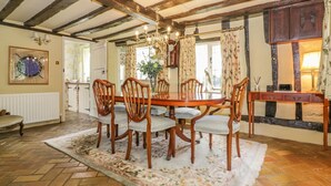 Ein traditioneller Essraum mit einem Holztisch, sechs Stühlen, einer Chandelüster und einem Teppich mit Blumenmuster.