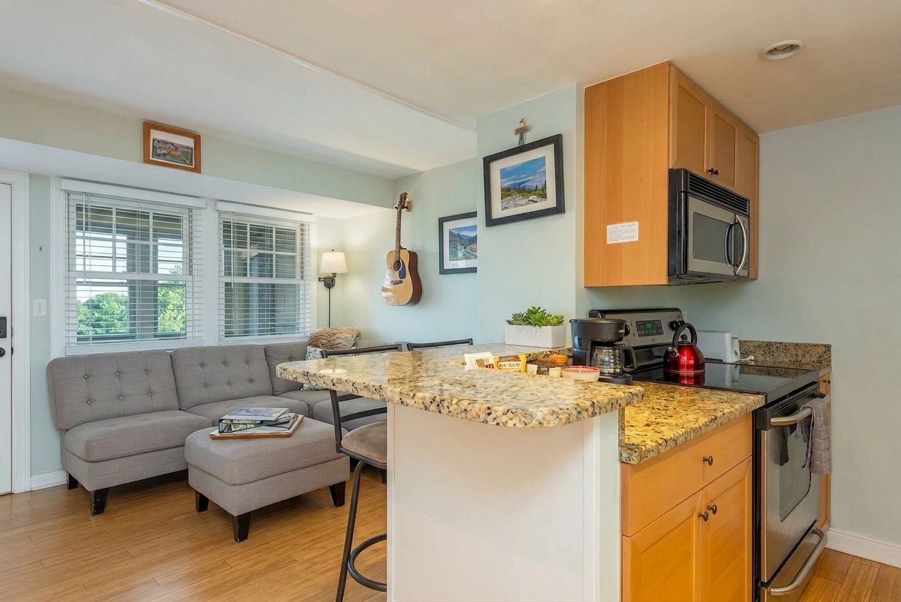 A compact kitchen with a granite countertop, wooden cabinets, and a built-in oven.