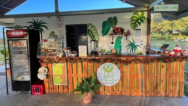 A reception area with a wooden counter, a sign reading "RECEPCIÓN," and a glass display case with items. - Villas Don Pablo (Las Tablas)