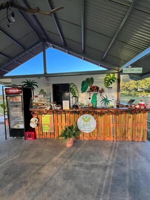 A reception area with a wooden counter, a sign indicating 'RECEPCIÓN,' and a vending machine labeled 'RECEPCIÓN.' - Villas Don Pablo (Las Tablas)