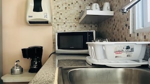 A compact kitchen with a microwave, coffee maker, and a stainless steel sink. - Villas Don Pablo (Las Tablas)