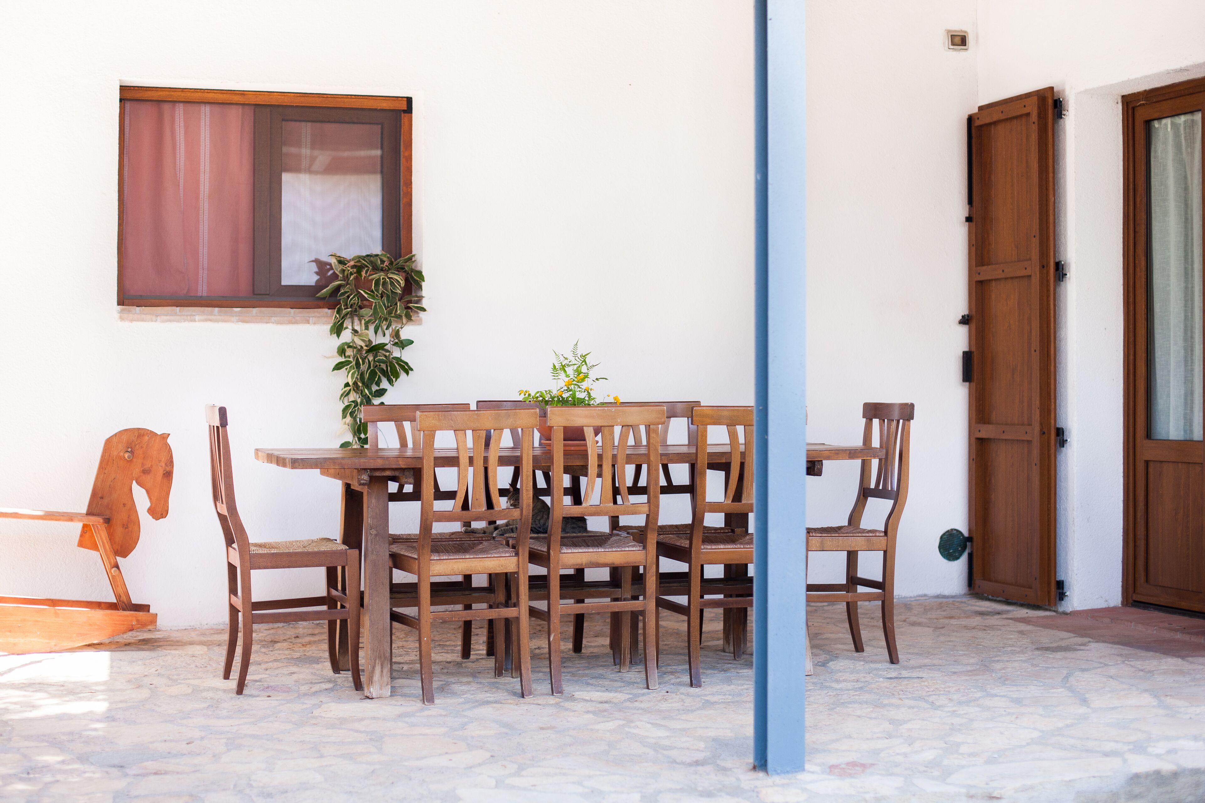 A wooden dining table with six chairs, a potted plant, and a horse-shaped decoration.