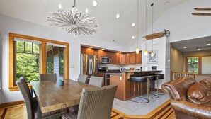 A modern kitchen with wooden cabinets, a central island, and pendant lighting. - Huge 7BR Mountain Lodge | Hot Tub, Fire Pit & Putting Green (Lincoln)