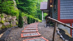 A pathway leading to a building with a red exterior and a wooden handrail. - Huge 7BR Mountain Lodge | Hot Tub, Fire Pit & Putting Green (Lincoln)