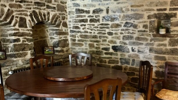 A stone-walled room with a round wooden table and chairs. - Apartment for two adults and two children ski Formigal Panticosa VTT (Senegüé)