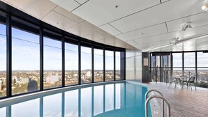 Piscina interior moderna con amplios ventanales que ofrecen vistas a la ciudad.