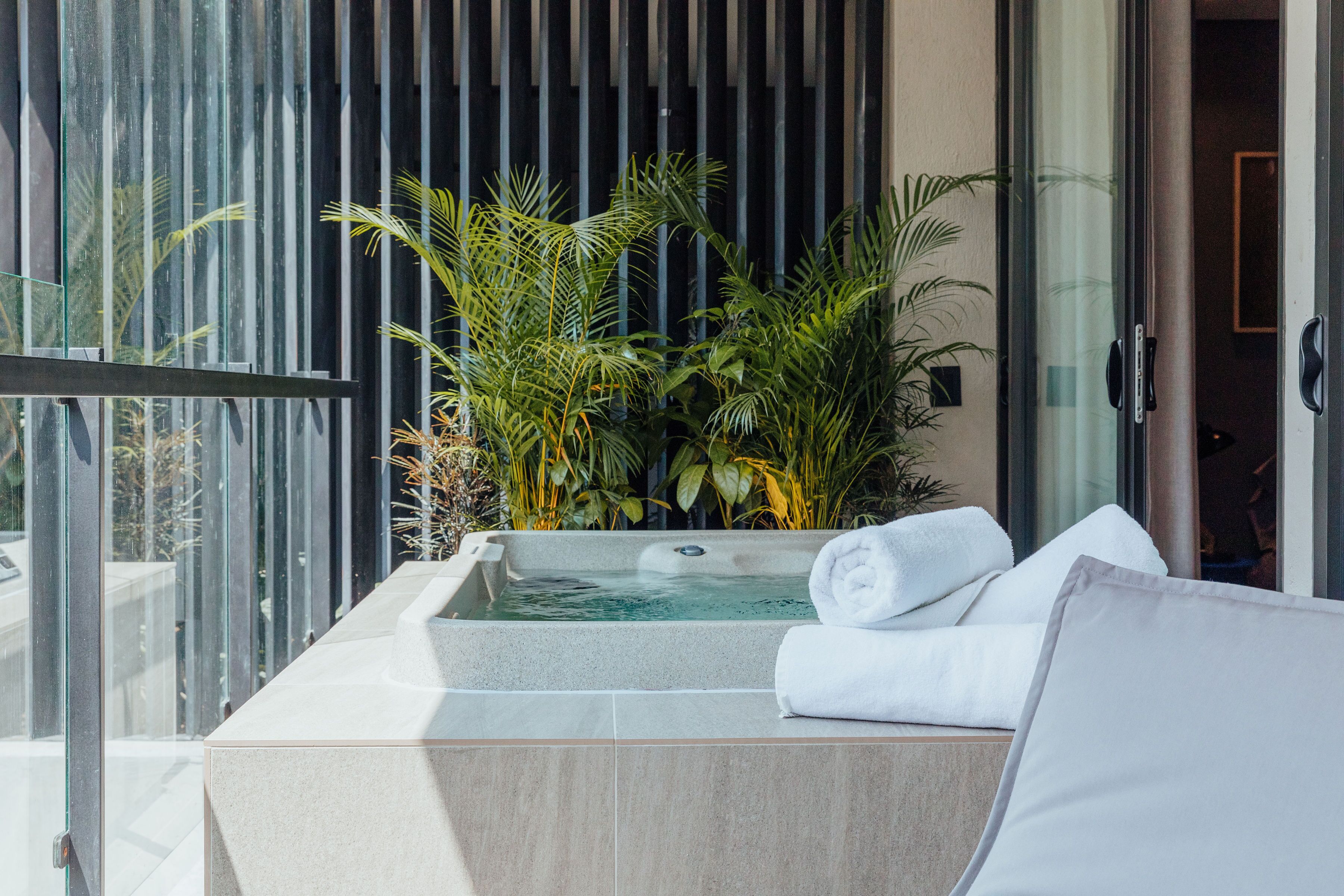 Un espace spa doté d’un bain à remous, de serviettes blanches et d’une végétation luxuriante.