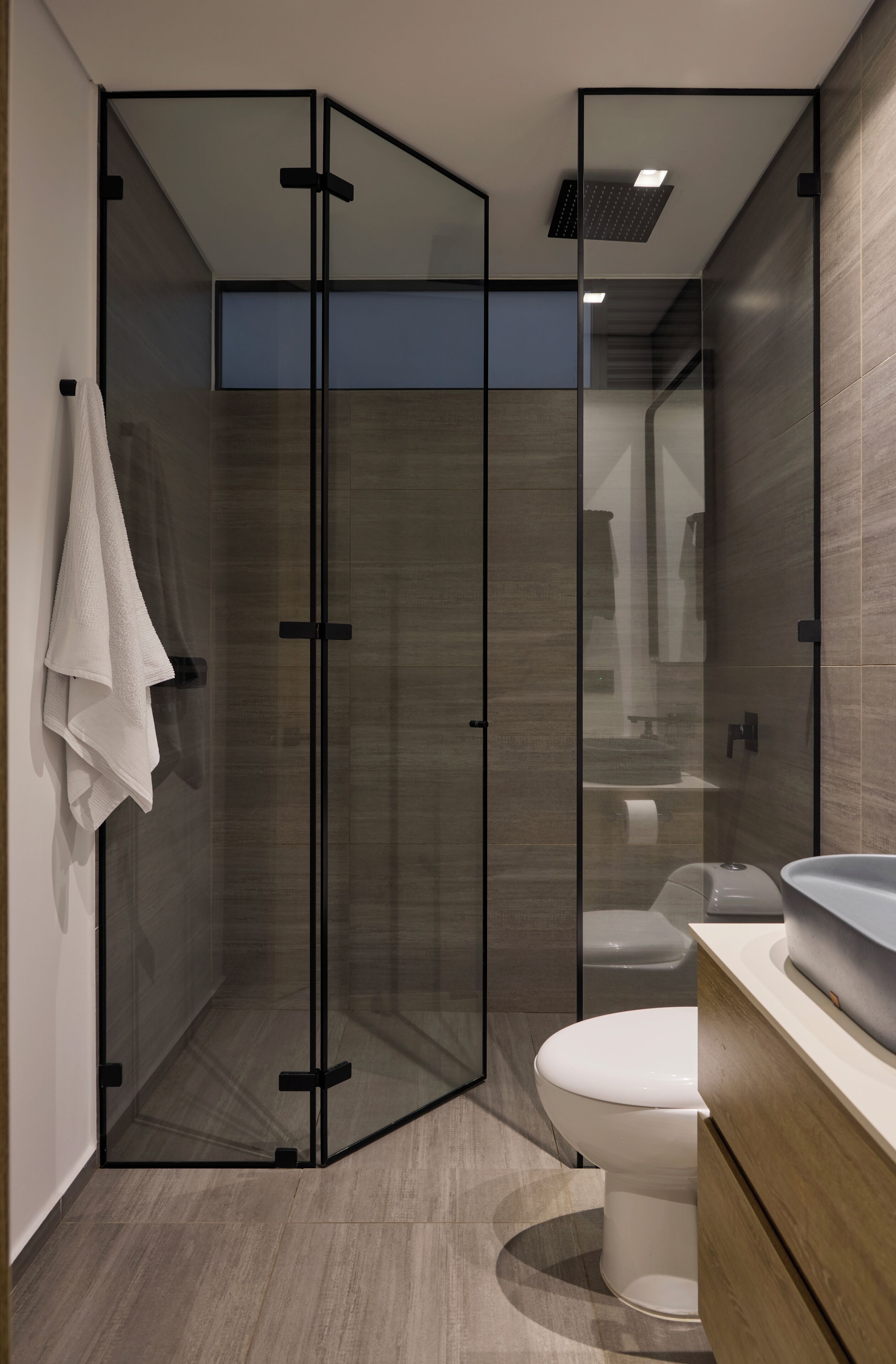 Ein modernes Badezimmer mit Duschkabine aus Glas, Toilette und Waschbecken.