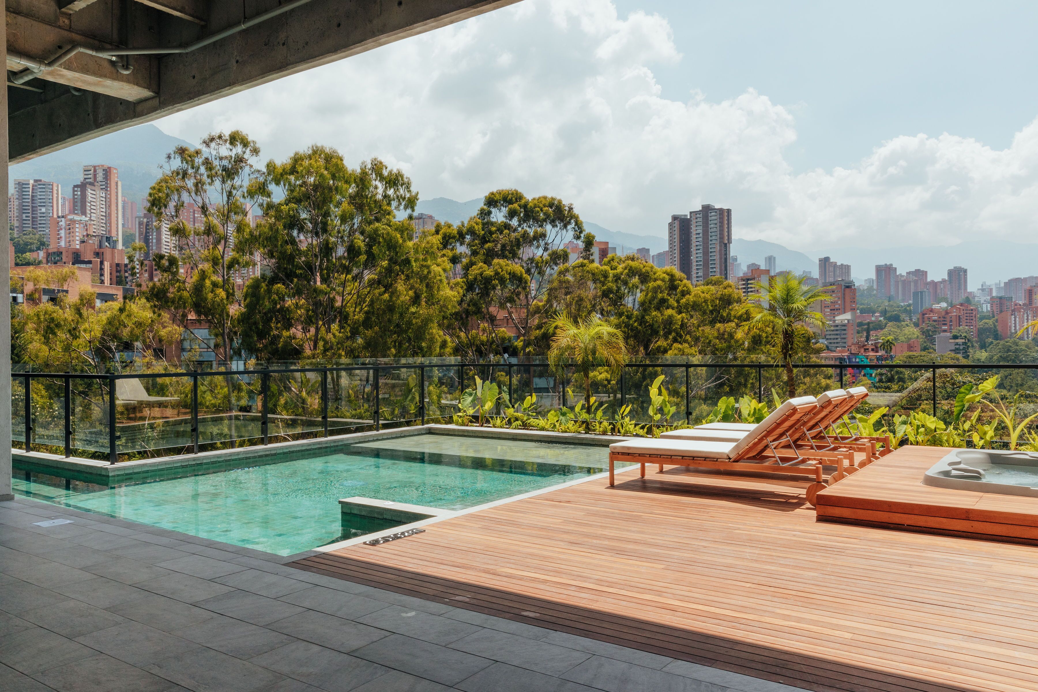 A rooftop pool with lounge chairs and a cityscape view.
