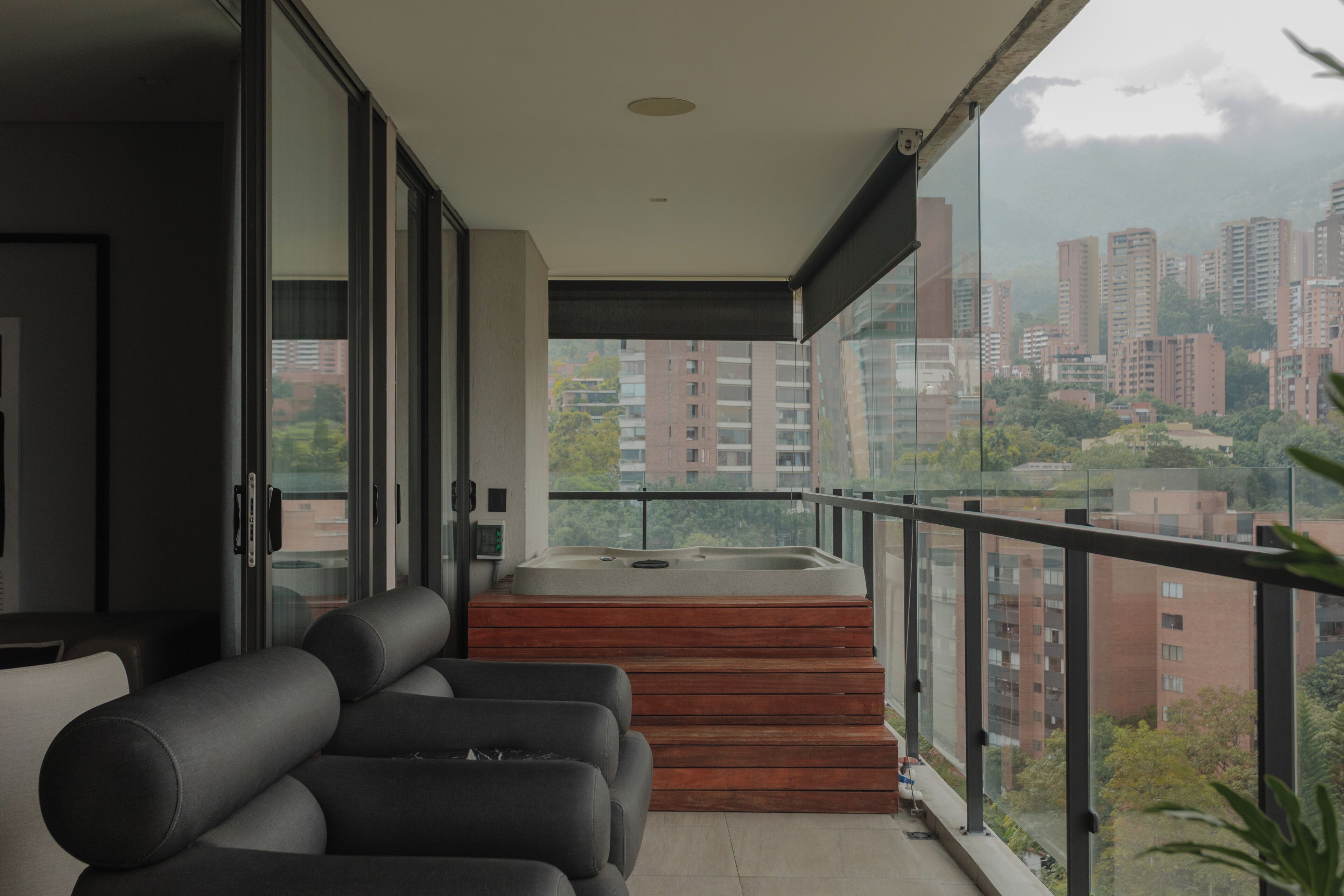 A balcony with a hot tub, seating area, and a city view.