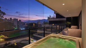 Un balcón moderno con hidromasaje, vistas a la ciudad y barandilla de vidrio.