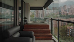 Un balcón moderno con jacuzzi, un sofá y vistas a la ciudad.