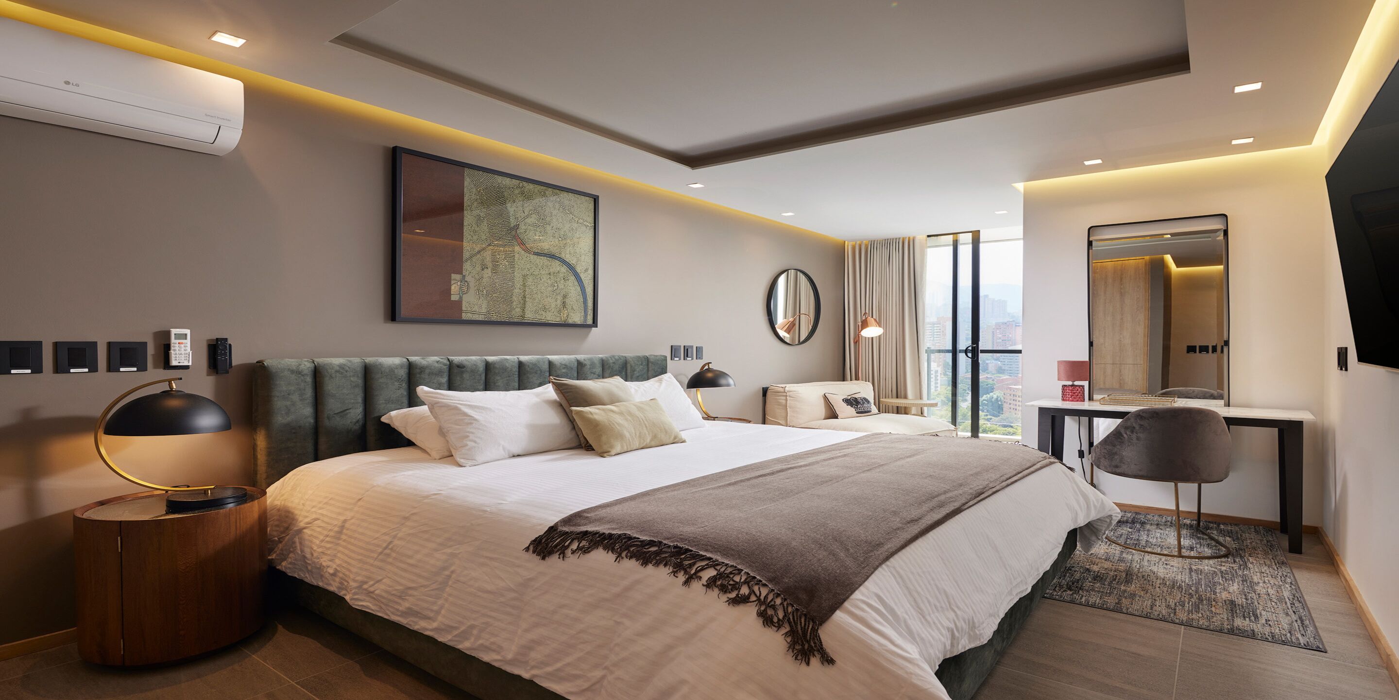 Quarto de hotel moderno com uma cama grande, uma escrivaninha, uma cadeira e uma janela ampla com vista para a cidade.