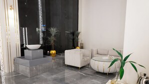 Una sala de estar moderna con piso de mármol, un sofá blanco, una mesa de centro redonda y un cuenco decorativo sobre un pedestal.